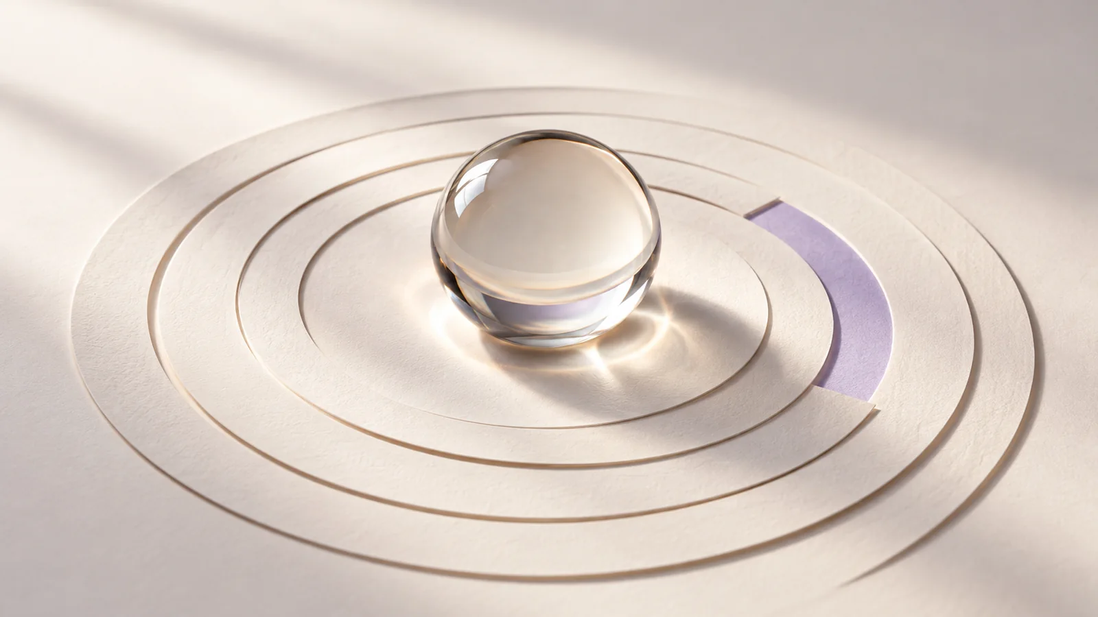 Clear glass sphere over ivory concentric paper rings with one lavender arc